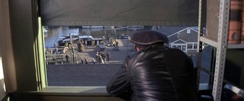 Movie still from “The Russians Are Coming the Russians Are Coming” (1966), directed by Norman Jewison – A man wearing a leather jacket looking out of a window; Wide shot, High angle