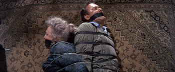 Movie still from “The Russians Are Coming the Russians Are Coming” (1966), directed by Norman Jewison – A man tied to a wall with a rope around his neck and tied to a woman; Medium shot, Overhead angle