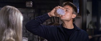 Movie still from “The Russians Are Coming the Russians Are Coming” (1966), directed by Norman Jewison – A man drinking from a plastic cup in front of a brick wall; Close Up shot, Low angle