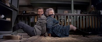 Movie still from “The Russians Are Coming the Russians Are Coming” (1966), directed by Norman Jewison – A man and a woman tied to the floor; Medium shot, High angle