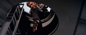 Movie still from “The Russians Are Coming the Russians Are Coming” (1966), directed by Norman Jewison – A man holding a camera up to the side of his face; Medium shot, Low angle