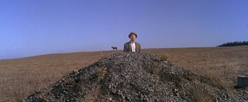 Movie still from “The Russians Are Coming the Russians Are Coming” (1966), directed by Norman Jewison – A man standing in front of a pile of rocks; Wide shot, Low angle