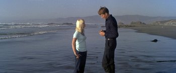 Movie still from “The Russians Are Coming the Russians Are Coming” (1966), directed by Norman Jewison – A man and a woman standing on a beach; Wide shot, Low angle