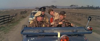Movie still from “The Russians Are Coming the Russians Are Coming” (1966), directed by Norman Jewison – A group of men riding in the back of an old car; Medium shot, High angle
