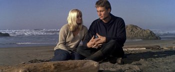 Movie still from “The Russians Are Coming the Russians Are Coming” (1966), directed by Norman Jewison – A man and a woman sitting on the beach; Medium shot, Low angle
