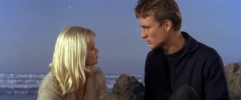 Movie still from “The Russians Are Coming the Russians Are Coming” (1966), directed by Norman Jewison – A man and a woman standing next to each other on the beach; Close Up shot, Low angle