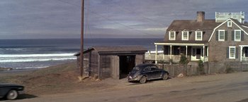Movie still from “The Russians Are Coming the Russians Are Coming” (1966), directed by Norman Jewison – An old car is parked in front of a shed; Extreme Wide shot, High angle