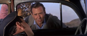 Movie still from “The Russians Are Coming the Russians Are Coming” (1966), directed by Norman Jewison – A reflection of a man in the rear view mirror of a car; Close Up shot, Over the shoulder angle