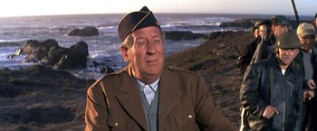 Movie still from “The Russians Are Coming the Russians Are Coming” (1966), directed by Norman Jewison – An older man wearing a hat and a jacket; Close Up shot, Over the shoulder angle