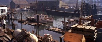 Movie still from “The Russians Are Coming the Russians Are Coming” (1966), directed by Norman Jewison – Several boats are docked at a pier in the water; Wide shot, High angle