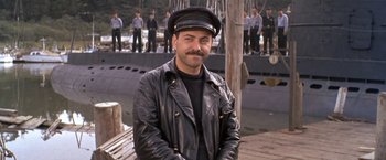 Movie still from “The Russians Are Coming the Russians Are Coming” (1966), directed by Norman Jewison – A man in a leather jacket and a hat; Medium shot, High angle