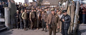 Movie still from “The Russians Are Coming the Russians Are Coming” (1966), directed by Norman Jewison – A group of men standing next to each other on a street; Wide shot, High angle