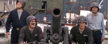 Movie still from “The Russians Are Coming the Russians Are Coming” (1966), directed by Norman Jewison – Two men are standing next to a large cannon; Medium shot, High angle