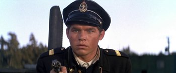 Movie still from “The Russians Are Coming the Russians Are Coming” (1966), directed by Norman Jewison – A person wearing a uniform and holding a gun; Close Up shot, Low angle