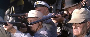 Movie still from “The Russians Are Coming the Russians Are Coming” (1966), directed by Norman Jewison – A man wearing a hat and holding a rifle; Close Up shot, Over the shoulder angle