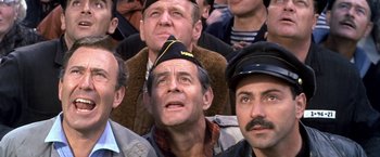 Movie still from “The Russians Are Coming the Russians Are Coming” (1966), directed by Norman Jewison – A group of men sitting next to each other in a crowd; Close Up shot, High angle