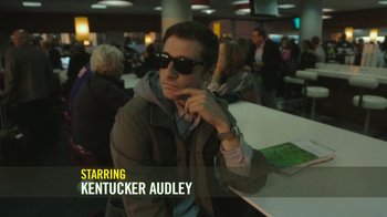 Movie still from “The Sacrament” (2013), directed by Ti West – A man sitting at a table in front of other people; Medium shot, Low angle