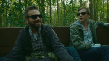 Movie still from “The Sacrament” (2013), directed by Ti West – Two men sitting on a bench in the woods; Medium shot, Over the shoulder angle