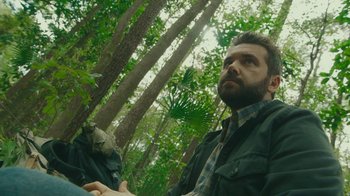 Movie still from “The Sacrament” (2013), directed by Ti West – A man sitting in the middle of a forest; Close Up shot, Low angle