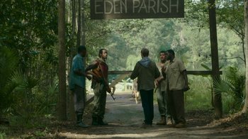Movie still from “The Sacrament” (2013), directed by Ti West – A group of men standing on a dirt road; Extreme Wide shot, Over the shoulder angle