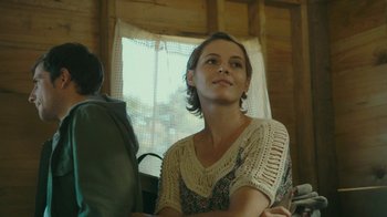 Movie still from “The Sacrament” (2013), directed by Ti West – A woman sitting in front of a window looking at something; Close Up shot, Over the shoulder angle