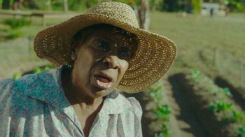 Movie still from “The Sacrament” (2013), directed by Ti West – An older woman wearing a straw hat in a field; Close Up shot, High angle