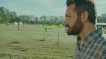 Movie still from “The Sacrament” (2013), directed by Ti West – A man with a goatee looks into the distance in a field; Close Up shot, Over the shoulder angle