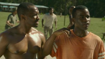Movie still from “The Sacrament” (2013), directed by Ti West – A couple of men standing next to each other; Medium shot, Over the shoulder angle
