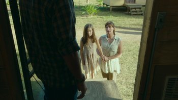 Movie still from “The Sacrament” (2013), directed by Ti West – A woman and a girl standing next to each other in a field; Medium shot, Over the shoulder angle