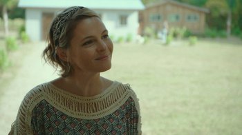 Movie still from “The Sacrament” (2013), directed by Ti West – A woman in a patterned dress looking to her left; Close Up shot, Over the shoulder angle