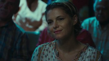 Movie still from “The Sacrament” (2013), directed by Ti West – A beautiful woman sitting in front of a group of people; Close Up shot, Over the shoulder angle
