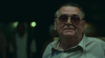 Movie still from “The Sacrament” (2013), directed by Ti West – An older man wearing glasses and a white shirt; Close Up shot, Over the shoulder angle