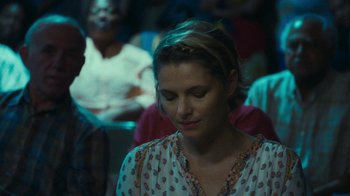Movie still from “The Sacrament” (2013), directed by Ti West – A person sitting in front of a crowd; Close Up shot, Over the shoulder angle