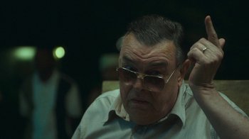 Movie still from “The Sacrament” (2013), directed by Ti West – An older man wearing sunglasses and a white shirt; Close Up shot, Over the shoulder angle