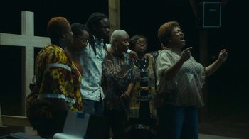 Movie still from “The Sacrament” (2013), directed by Ti West – A group of people standing next to each other on a stage; Medium shot, Low angle