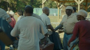 Movie still from “The Sacrament” (2013), directed by Ti West – A group of men standing next to each other holding suitcases; Medium shot, Over the shoulder angle