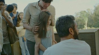 Movie still from “The Sacrament” (2013), directed by Ti West – A young girl getting her hair combed by an adult; Medium shot, Over the shoulder angle