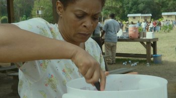 Movie still from “The Sacrament” (2013), directed by Ti West – A woman in a white shirt is putting something in a white bowl; Close Up shot, High angle
