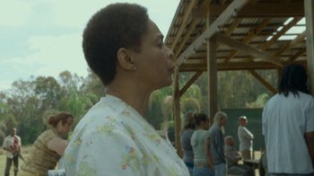 Movie still from “The Sacrament” (2013), directed by Ti West – An older woman is blowing a kiss at the park; Close Up shot, Over the shoulder angle