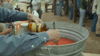Movie still from “The Sacrament” (2013), directed by Ti West – A person pouring a large amount of sauce into a large metal tub; Extreme Close Up shot, High angle