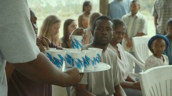 Movie still from “The Sacrament” (2013), directed by Ti West – A group of people standing in a room with cups on a tray; Medium shot, Over the shoulder angle