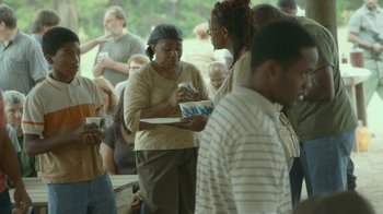Movie still from “The Sacrament” (2013), directed by Ti West – A group of people standing in a room; Medium shot, Over the shoulder angle