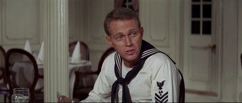 Movie still from “The Sand Pebbles” (1966), directed by Robert Wise – A man in a sailor's uniform sitting at a dining table; Close Up shot, Over the shoulder angle