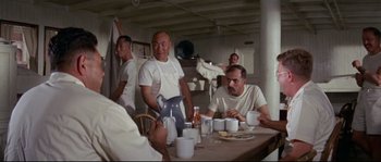Movie still from “The Sand Pebbles” (1966), directed by Robert Wise – A group of men sitting at a table with cups; Wide shot, Low angle
