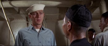 Movie still from “The Sand Pebbles” (1966), directed by Robert Wise – A man wearing a sailor's hat and a blue shirt; Close Up shot, Over the shoulder angle