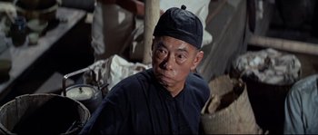 Movie still from “The Sand Pebbles” (1966), directed by Robert Wise – An older man wearing a black hat and a black shirt; Close Up shot, Low angle