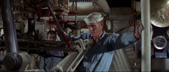 Movie still from “The Sand Pebbles” (1966), directed by Robert Wise – A man working on a machine in an industrial setting; Medium shot, Low angle