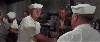 Movie still from “The Sand Pebbles” (1966), directed by Robert Wise – A man in a white hat is holding a spoon in his hand; Medium shot, Low angle