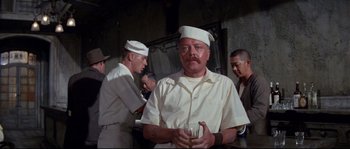 Movie still from “The Sand Pebbles” (1966), directed by Robert Wise – A man with a beard and mustache holding a drink; Medium shot, Over the shoulder angle