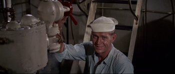 Movie still from “The Sand Pebbles” (1966), directed by Robert Wise – A man wearing a sailor's hat is holding a fire hydrant; Medium shot, High angle